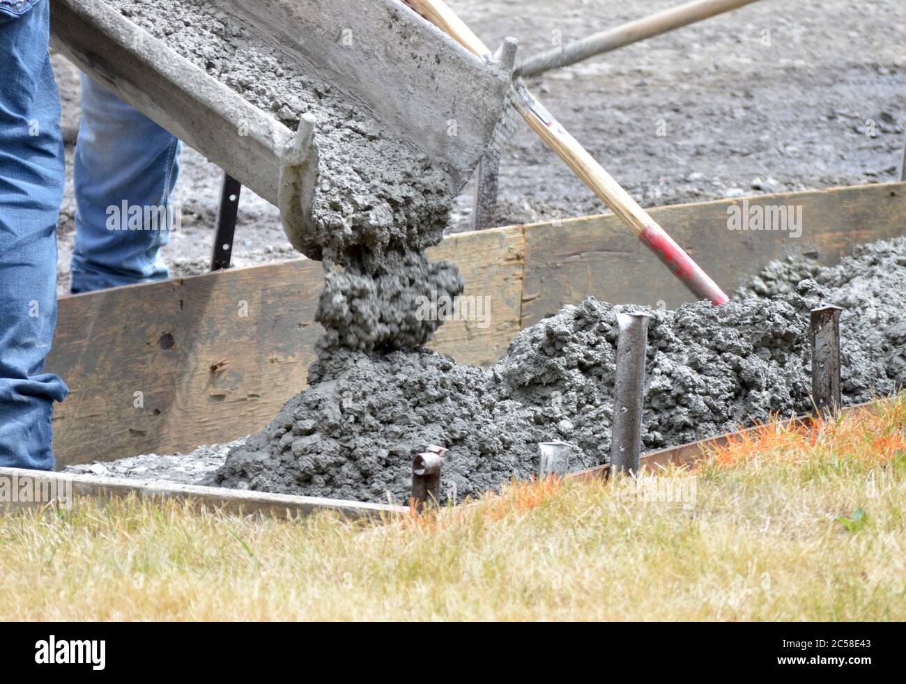Workers pour cement into mold of a new sidewalk. Photo shows motion of