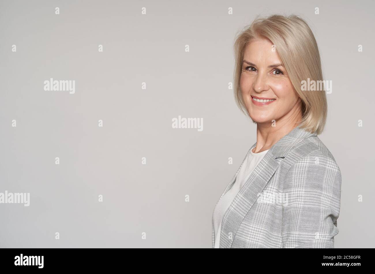 Senior blonde woman is toothy smiling isolated on grey background Stock Photo