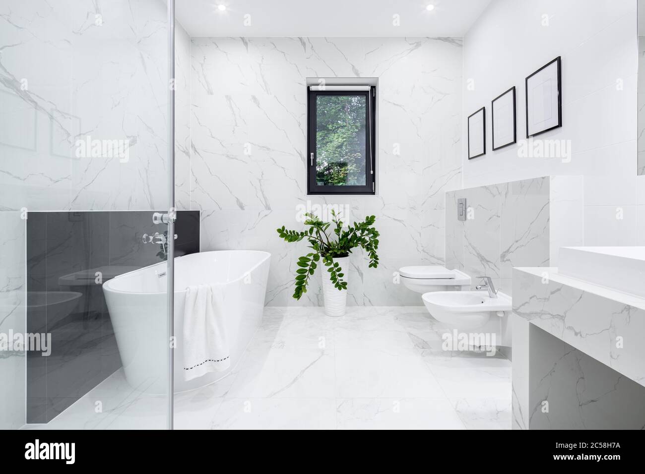 Luxury white bathroom with big bathtub and marble style tiles Stock