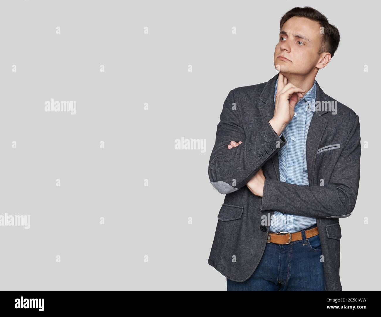 Handsome man in a stylish clothes is looking aside and thinking. Studio isolated Stock Photo