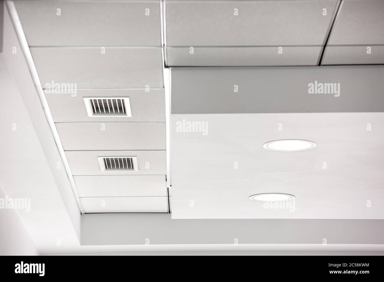 multi-level gypsum plasterboard ceiling and a white square tile suspended  ceiling with integrated lighting lamps and ventilation grilles, close up  det Stock Photo - Alamy