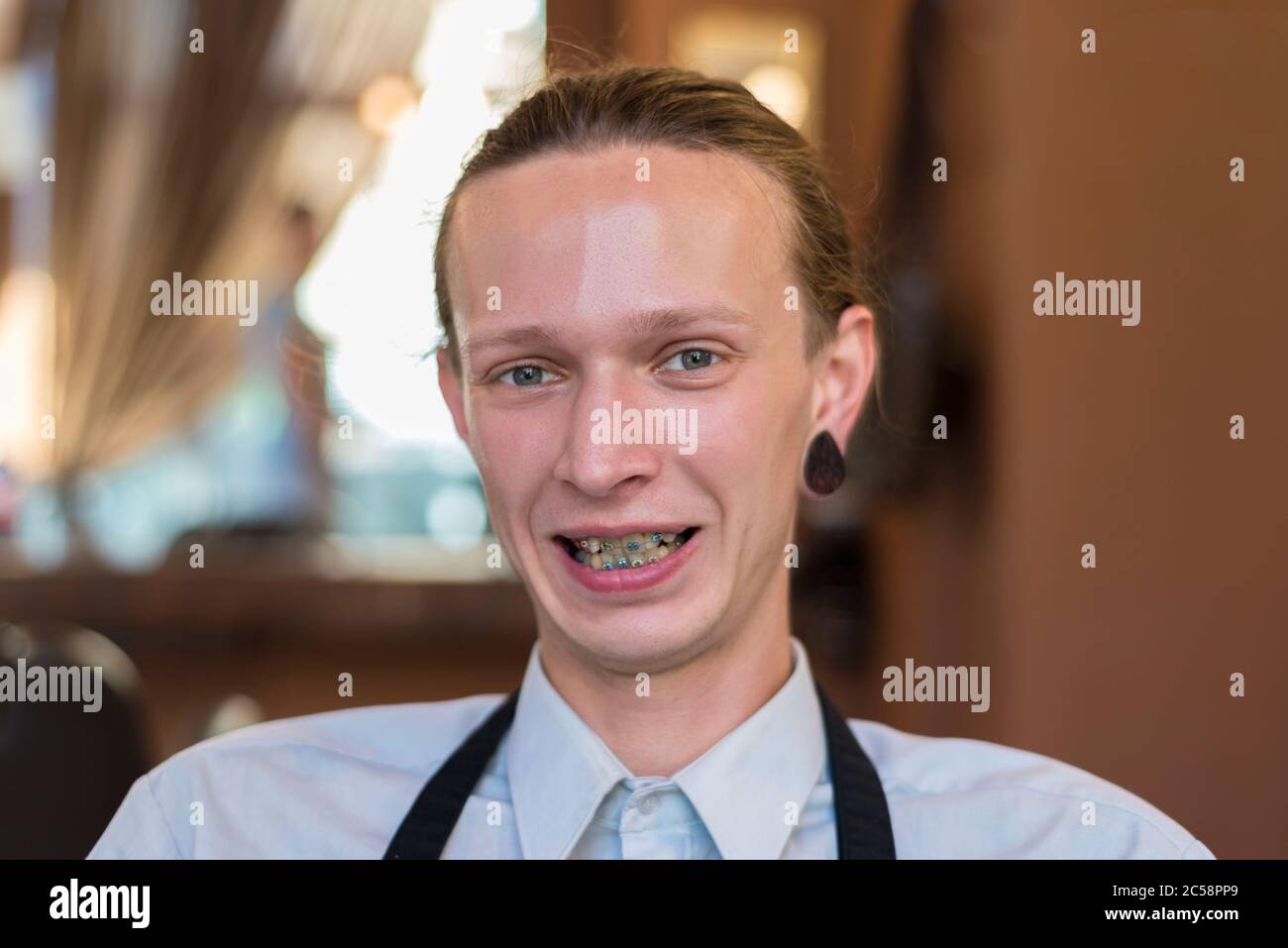 Portrait of a twenty five year old guy with braces on his teeth, smiling. Wrong bite in a young smiling guy. Dental pathology, correction of Stock Photo