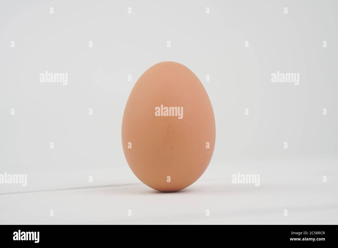 Close-up view of raw chicken eggs in egg box on white wooden background ...
