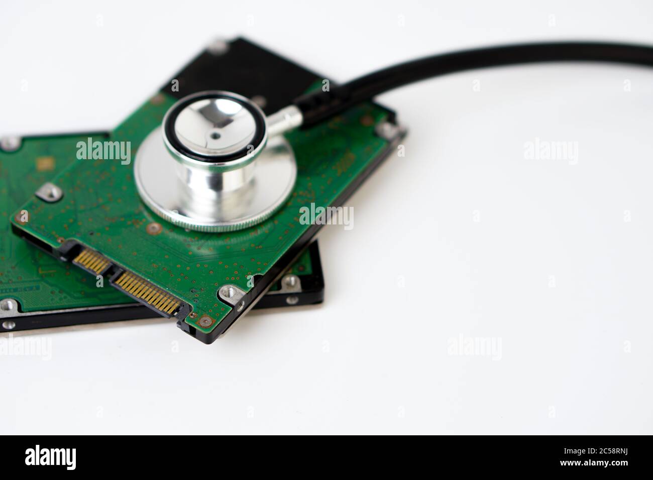A hard disk with a stethoscope isolated on white background. Recovery and Data Safety Stock Photo