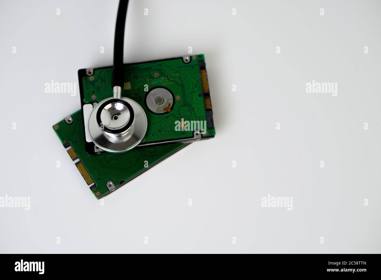 A hard disk with a stethoscope isolated on white background. Recovery and Data Safety Stock Photo