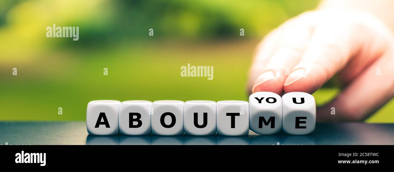 Hand turns dice and changes the expression "about me" to "about you". Stock Photo