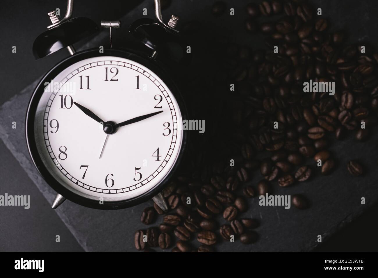 vintage alarm clock and coffee beans on slate stone plate. Selective Focus. Copy Space concept. Celebrate International Coffee Day On October Stock Photo