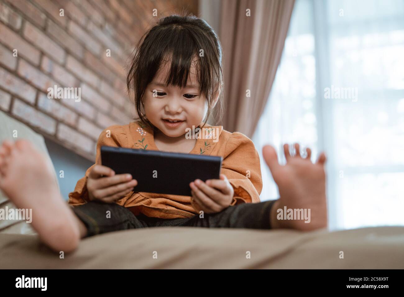 little girl laughed happily when holding a phone to see the child's video Stock Photo