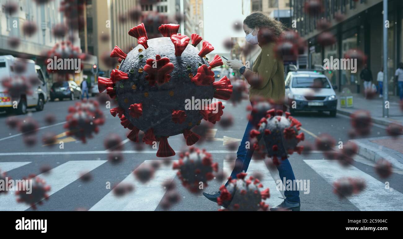 Covid-19 cells against woman wearing face mask using smartphone Stock Photo