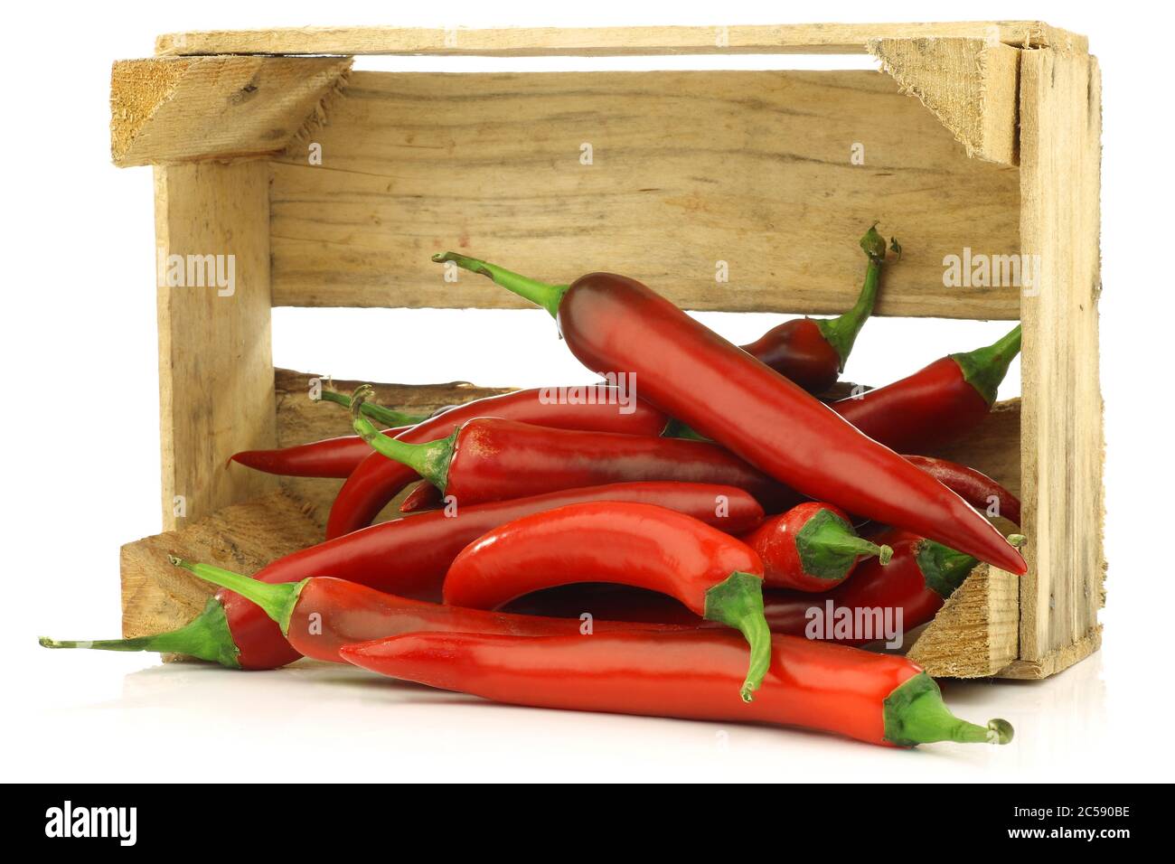 fresh red chili peppers in a wooden crate on a white background Stock ...