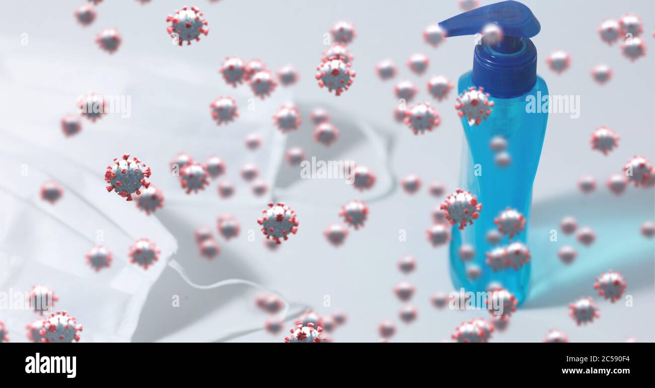 Covid-19 cells against bottle of sanitizer and face masks Stock Photo