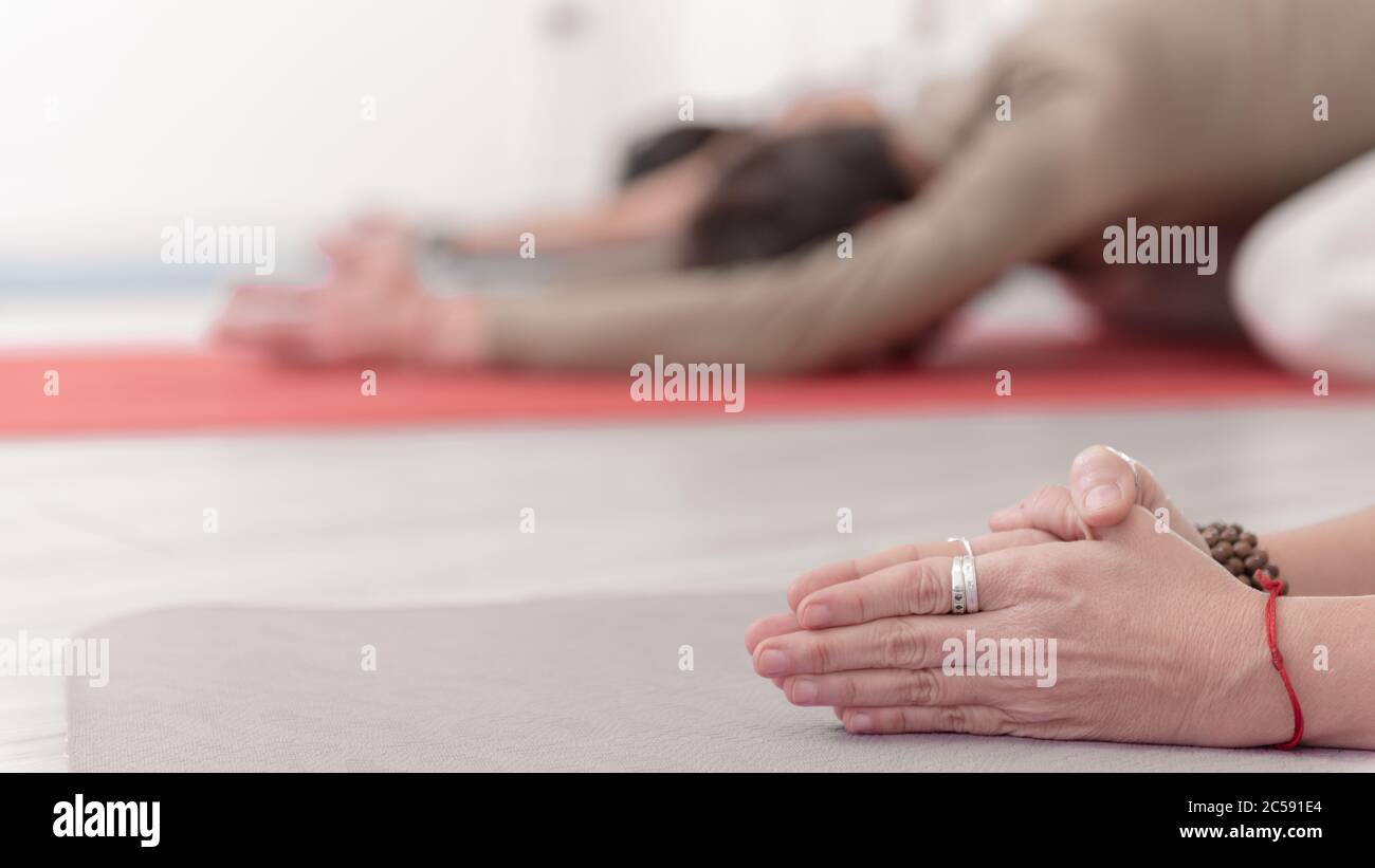 Close-up of feminine and masculine arms during meditation. Shashankasana position. Rabbit Pose. Seguence of Surya namaskar. Greeting to the Sun. How Stock Photo