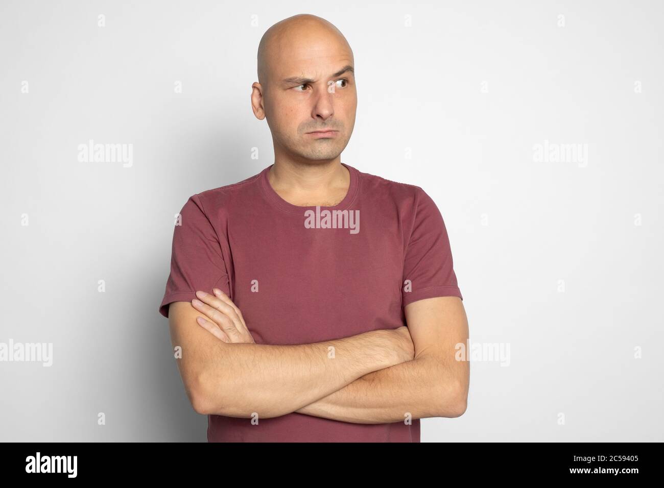 Serious bald man looking aside with suspicion. Isolated on grey studio background Stock Photo