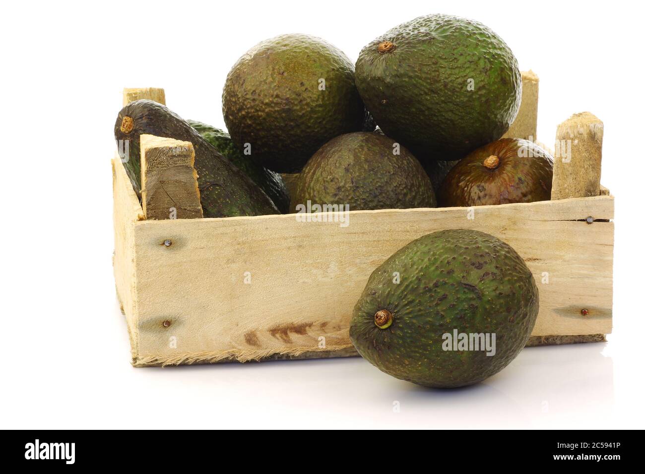fresh and ripe avocado's in a wooden crate on a white background Stock Photo