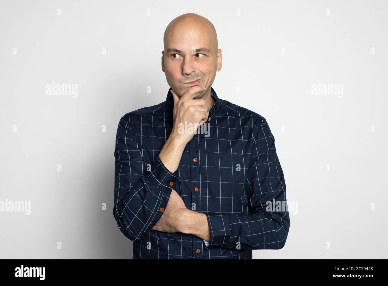 Middle aged bald male with skeptic look. Man has some doubts, looks curiously aside, isolated Stock Photo
