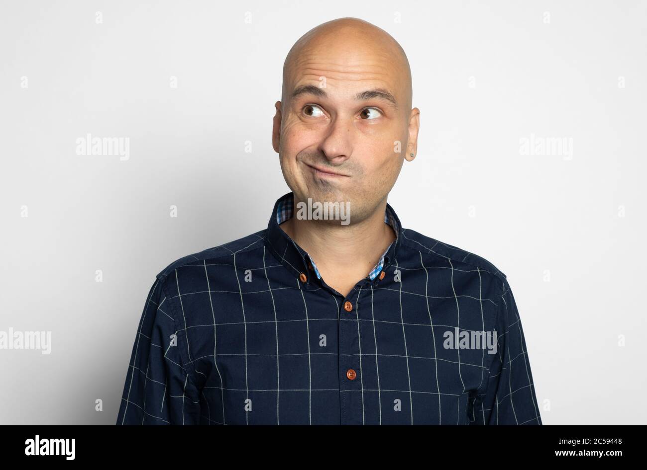 portrait of a bald guy smirking. Man looking away isolated on grey studio background Stock Photo
