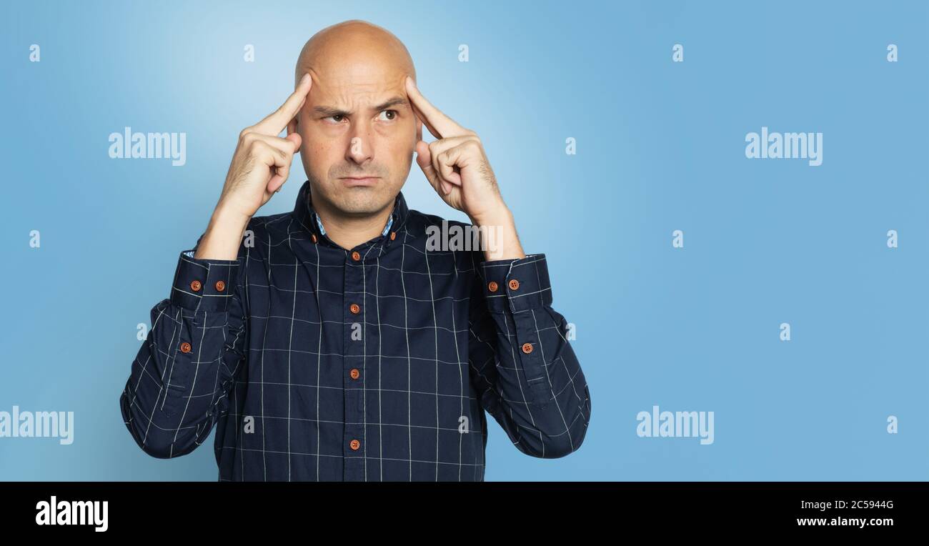 Serious middle aged bald man thinking. Isolated over blue studio background Stock Photo