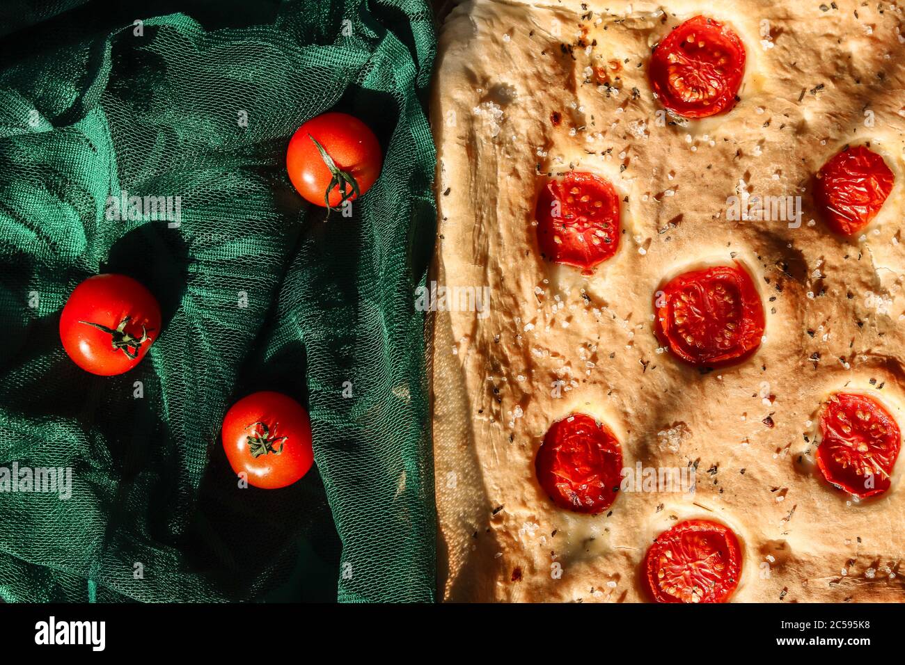 Focaccia italian bread with cherry tomatoes on a green guipure lace cloth. Stock Photo
