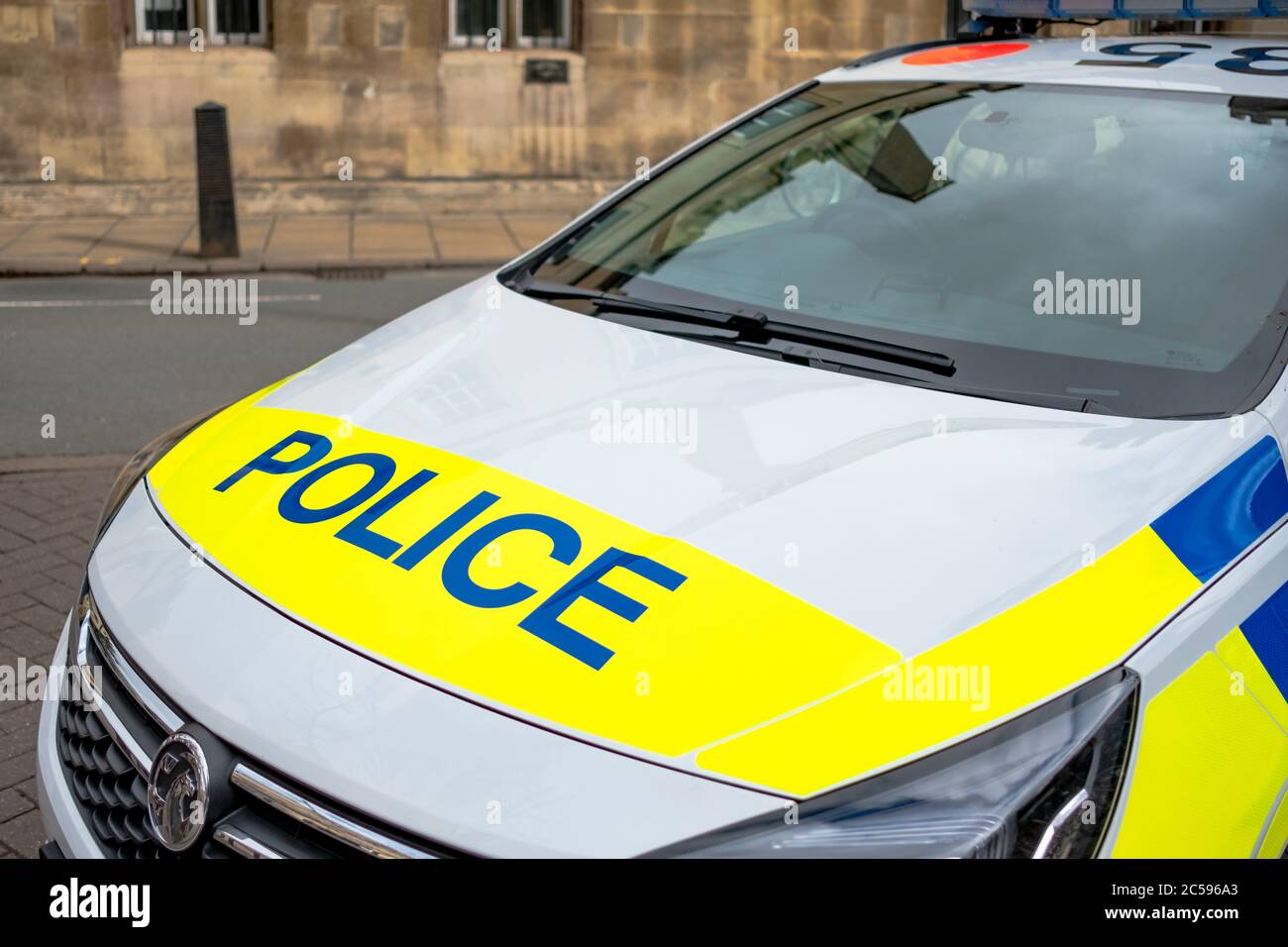 Detailed view of a British Police Vehicle seen parked near a busy street, responding to an emergency call. Detail of the hood and decals are evident. Stock Photo