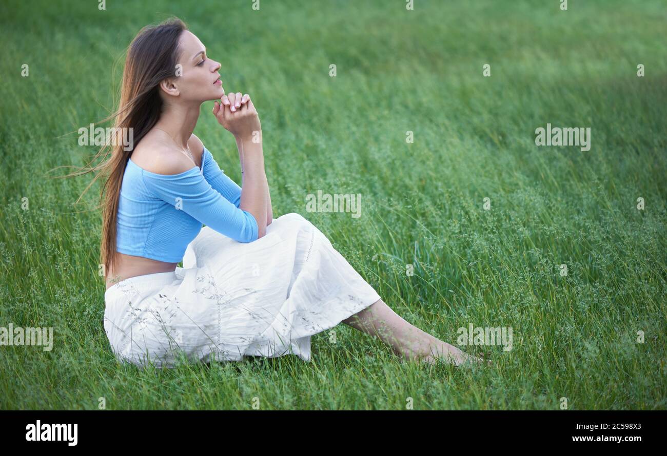 Pretty woman is relaxing in the park. Girl sitting on a grass Stock ...