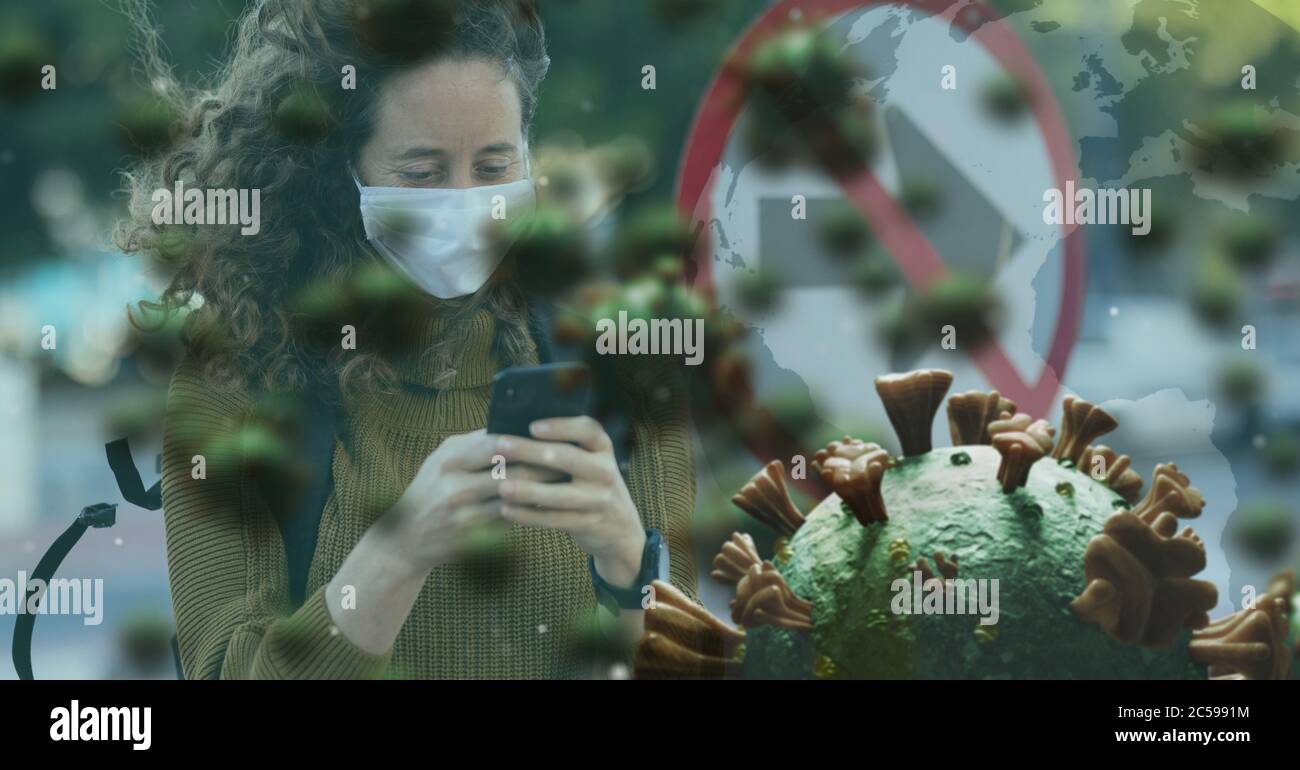 Covid-19 cells against woman wearing face mask using smartphone Stock Photo