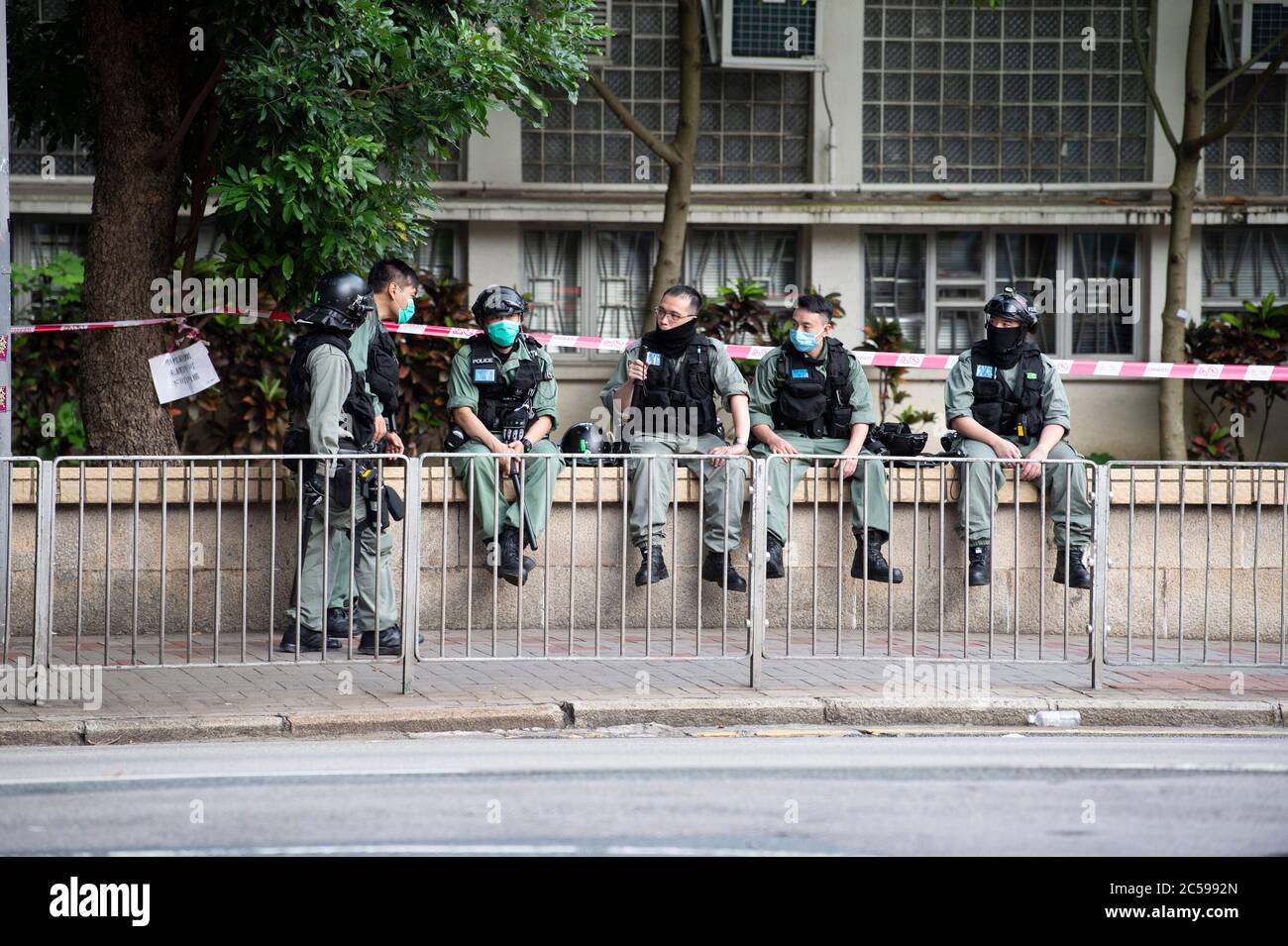 HONG KONG, HONG KONG SAR, CHINA: JULY 1st 2020.Police deal with the illegal protest march and are easily exhausted by the 34 Degree heat.Hong Kong Special Administrative Region Establishment Day. Twenty-three years after Hong Kong was handed by Britain back to Chinese rule, Beijing is pushing to implement tough new national security laws that will suppress the pro-democracy protests seen in the city. It will shatter the Sino-British Joint Declaration where China agreed to the One country, Two systems government. The banning of traditional marches for the first time, has infuriated the public.  Stock Photo