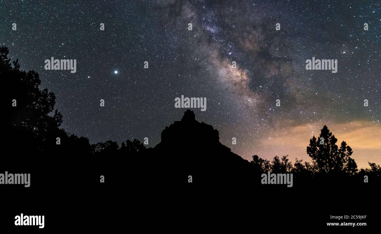 The Milkyway rises of Bell Rock in Sedona, Arizona. Jupiter and Saturn visible to the top left. Stock Photo