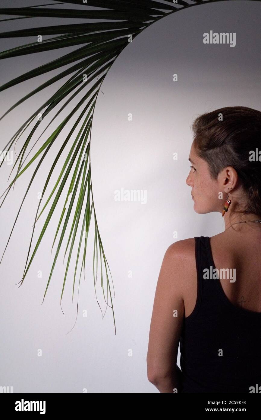 profile of woman with shaved head at home with palm leaf Stock Photo