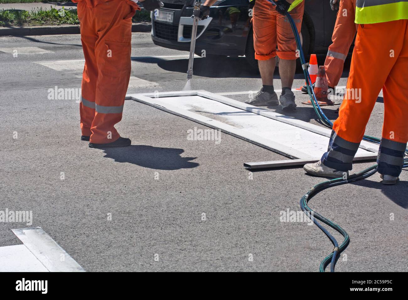 Workers are painting a stop line in a city street. Stock Photo