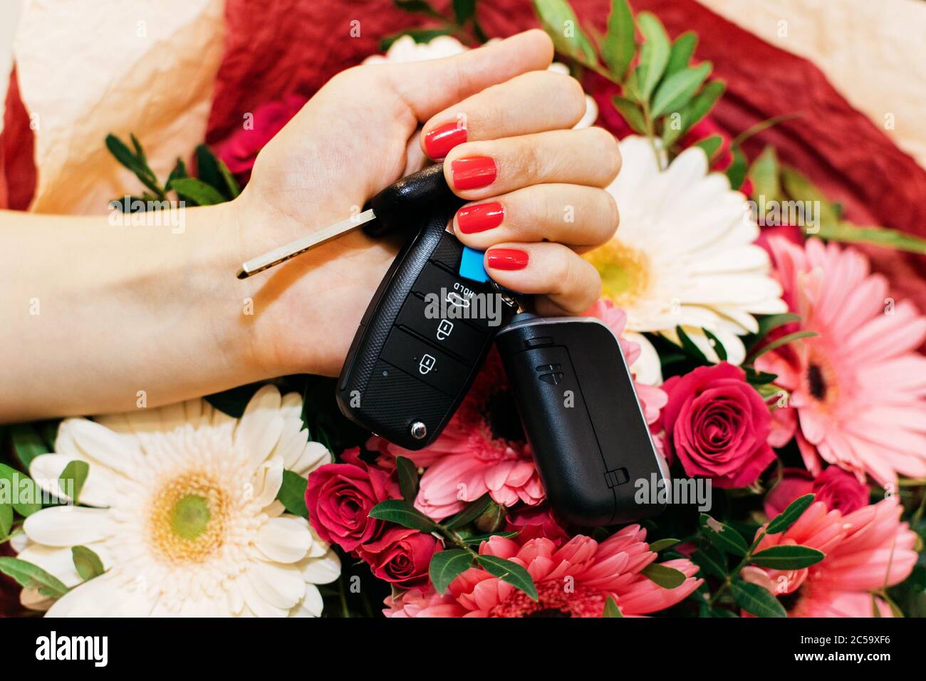 Car keys in a female hand with flowers Stock Photo