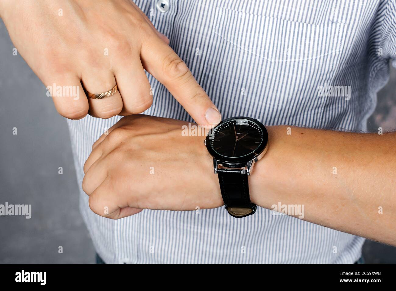 A man in a shirt points to a wristwatch Stock Photo