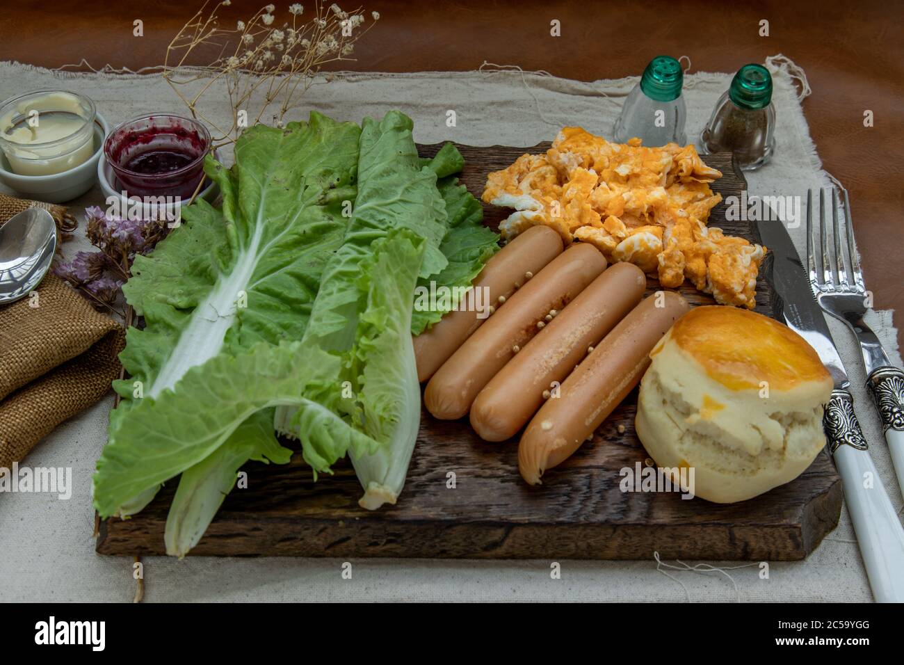 Continental breakfast with scrambled eggs, fried sausages, vegetable and scones on Wooden background, Selective focuse. Stock Photo