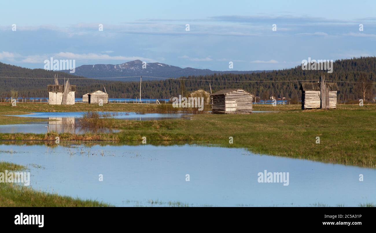 Water from a flooded river cover a delta land. Wooden barns on the