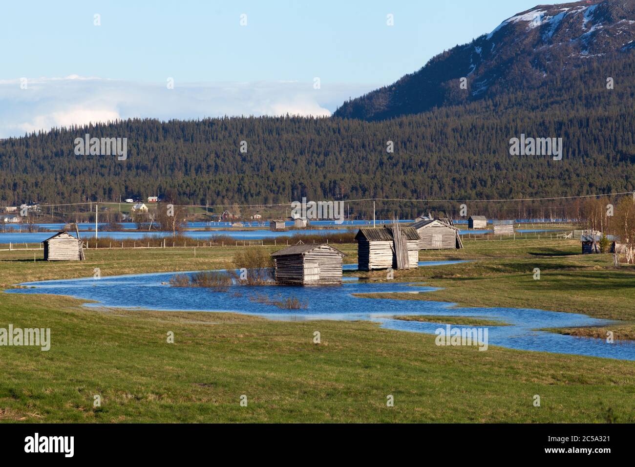 Water from a flooded river cover a delta land. Wooden barns on the