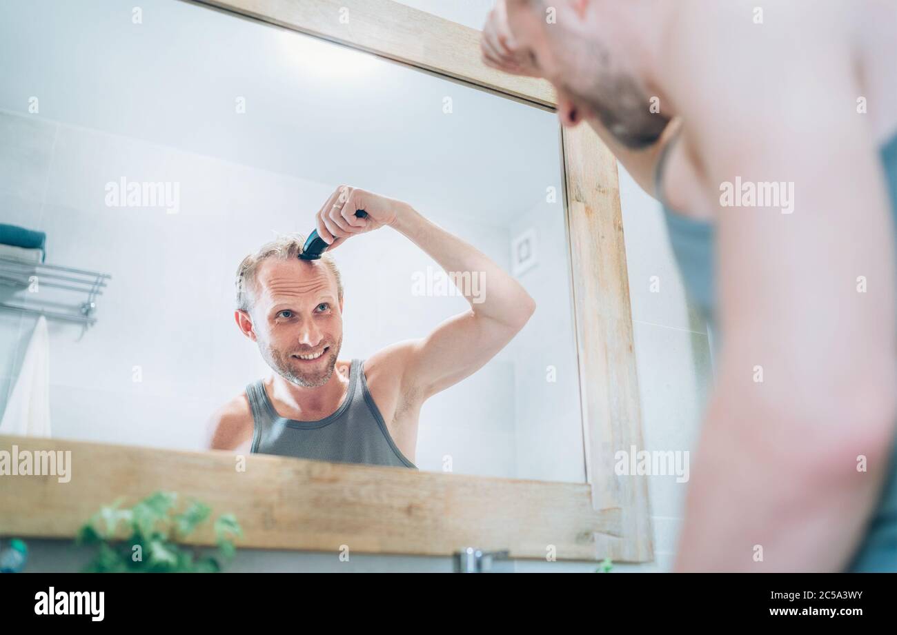 Smiling Man making new style haircut trimming a hairs using an electric
