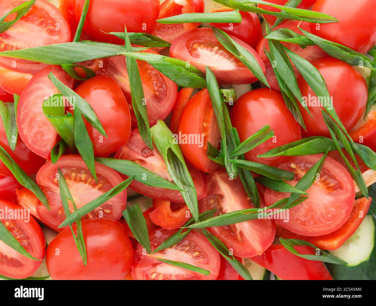 Tomato, green onion, cucumber, pepper slices. Natural background with slices of tomato, green onion. Fresh vegetable salad. Stock Photo