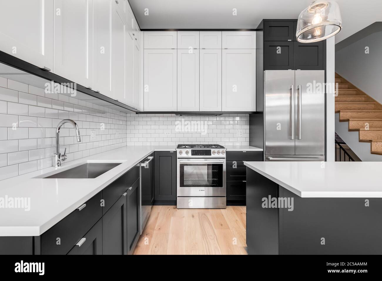A modern kitchen with white and black cabinets, stainless steel Bosch