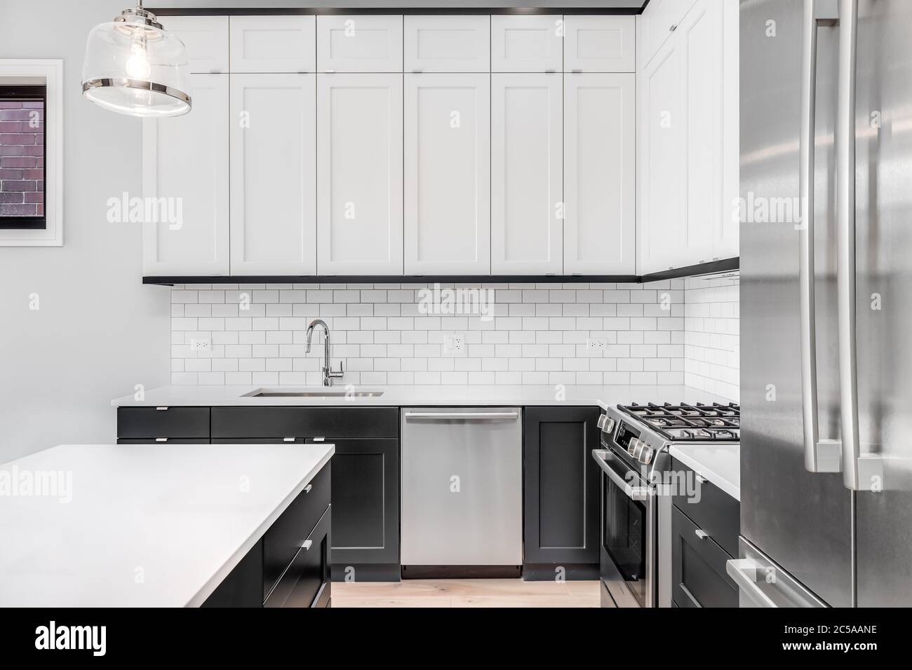 A modern kitchen with white and black cabinets, stainless steel Bosch ...