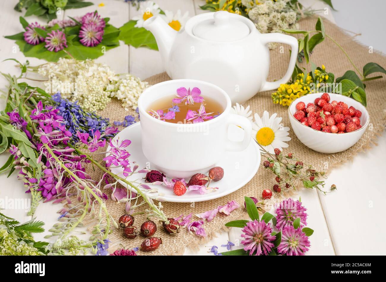 Herbal tea in a white cup with flowers. Tea ceremony. Tea with chamomile, with wild rose and clover Stock Photo
