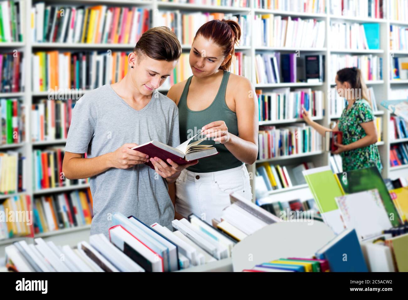 Portrait happy teenager girl and boy holding open textbook in hands in ...