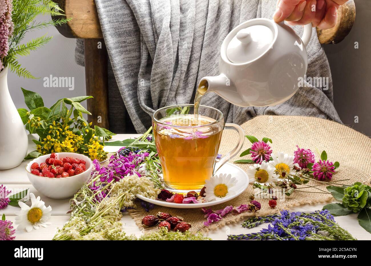 A woman pours herbal tea with chamomile, rosehip, clover. Tea ceremony. Summer drink Stock Photo