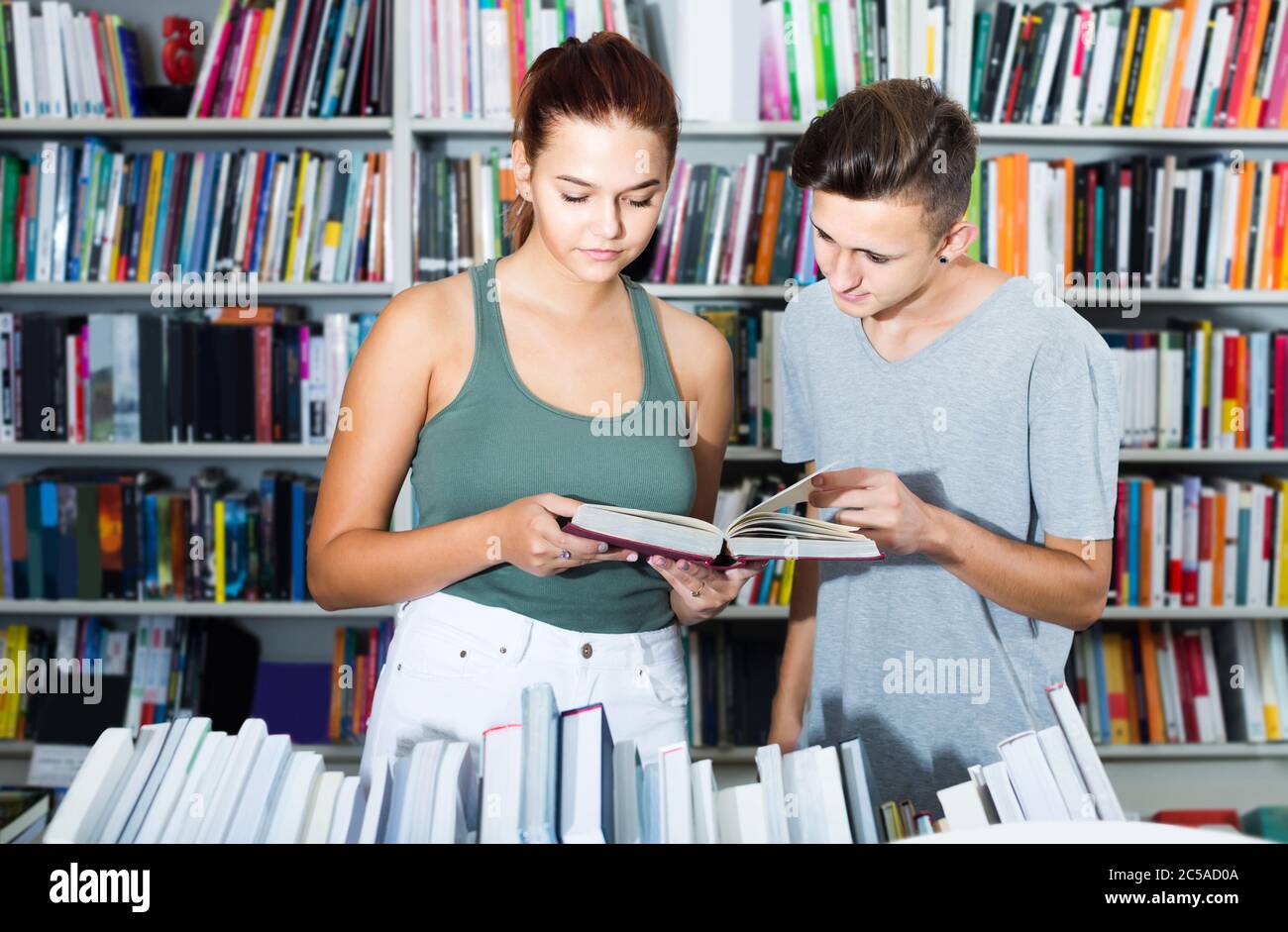 portrait of happy spanish teenage boy and girl customers looking at ...