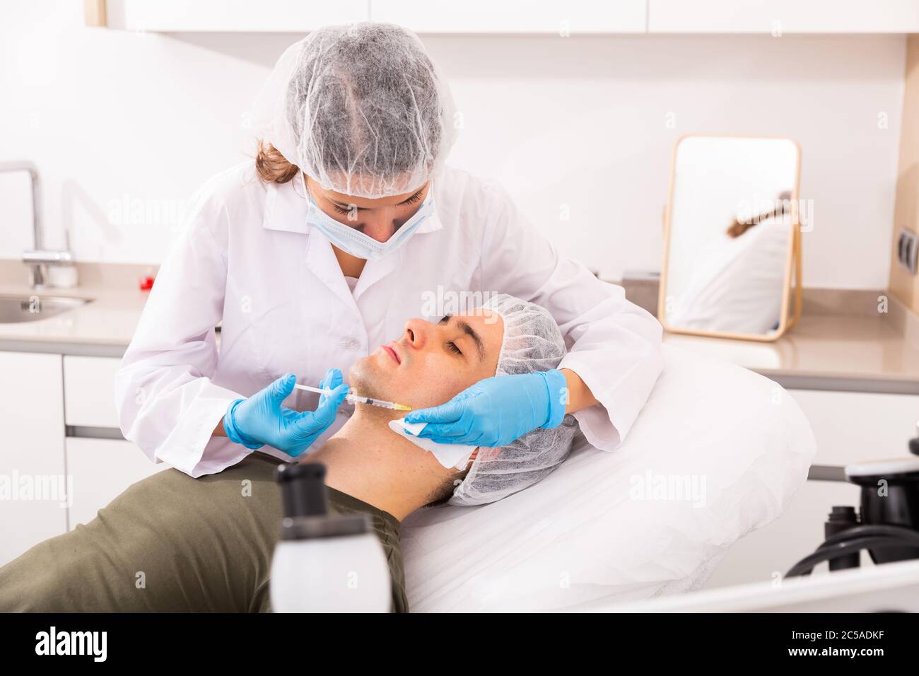 Professional female beautician performing face contouring injections to