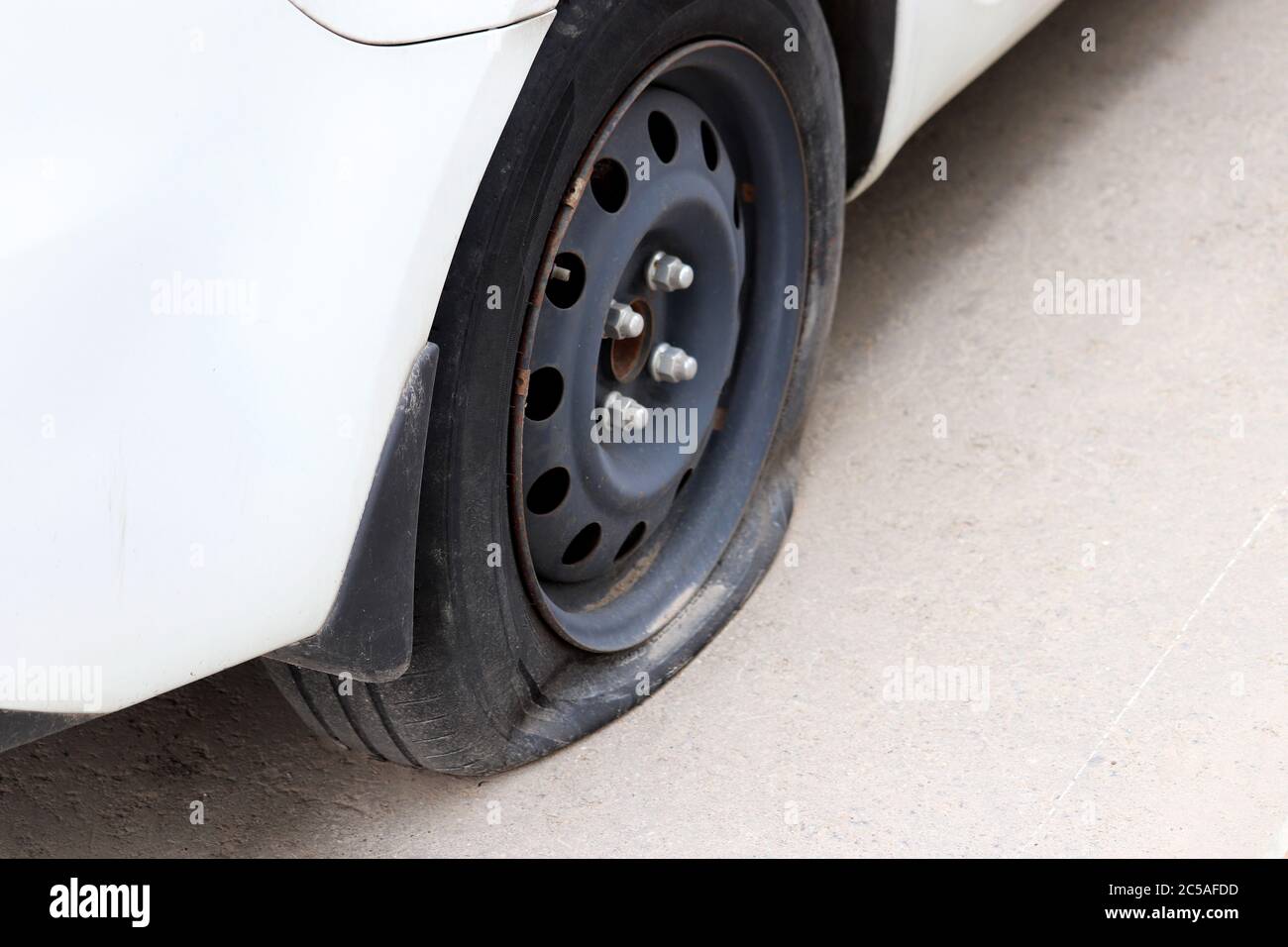 Car wheel with a flat tire on the street. Road accident, auto breakdown Stock Photo