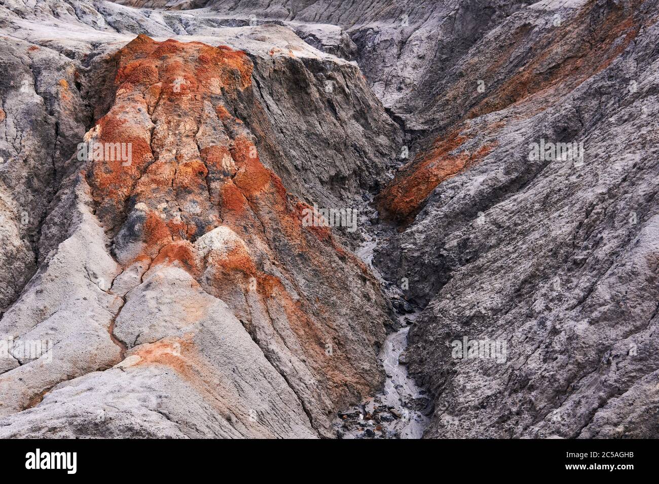 streams of water formed a gully in a clay slope devoid of soil Stock Photo