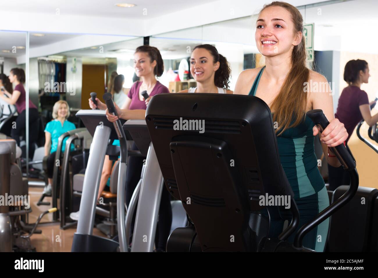 Group of cheerful women using cross-trainers in sport club Stock Photo ...