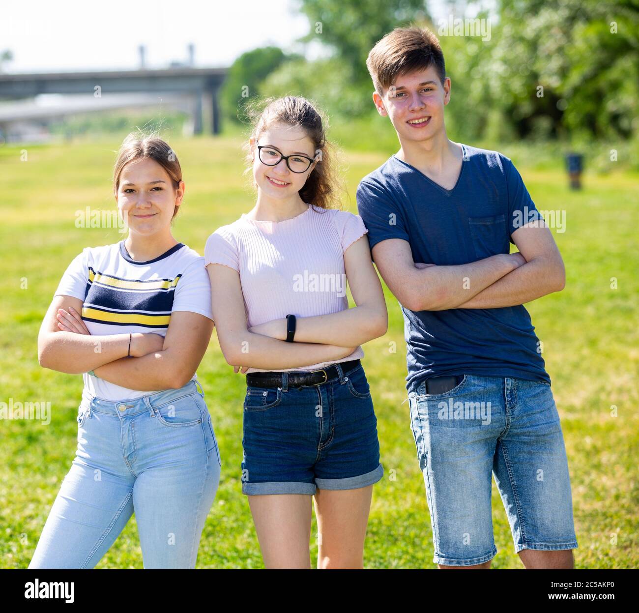 Three positive teenagers posing on the spring park lawn Stock Photo - Alamy
