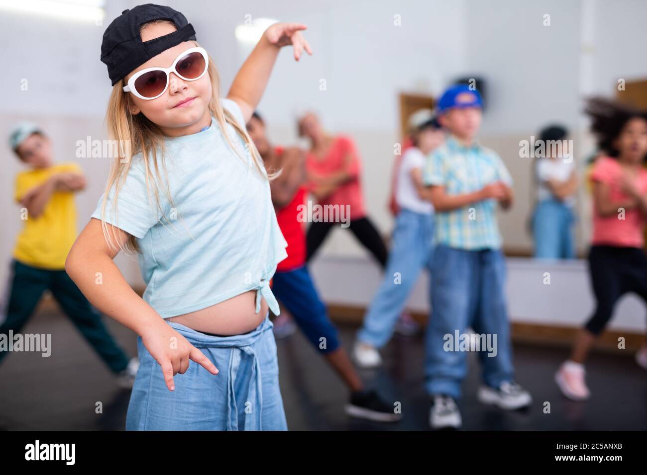 Little girl hip hop dancer in casual clothes and cap exercising with