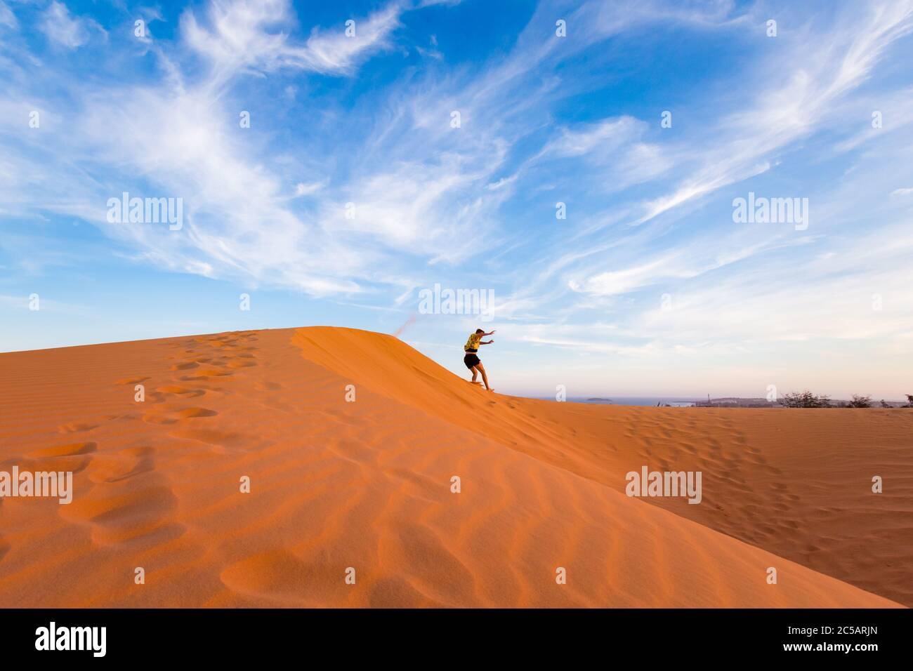 Young handsome man having fun on Red sand dunes in Mui Ne, Phan Tiet ...