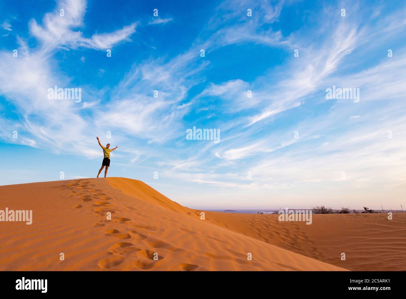 Young handsome man having fun on Red sand dunes in Mui Ne, Phan Tiet ...